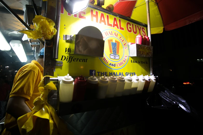 a yellow stand has lots of plastic containers filled with condiments