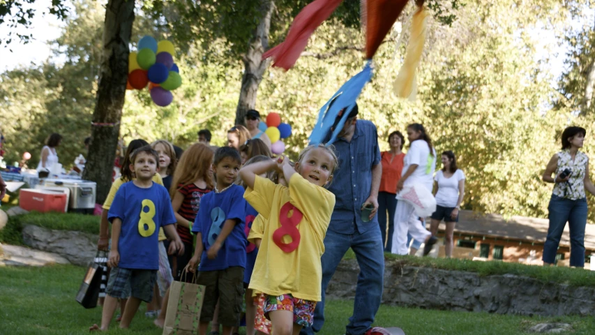 young children and adults gather in an outdoor area at a birthday party