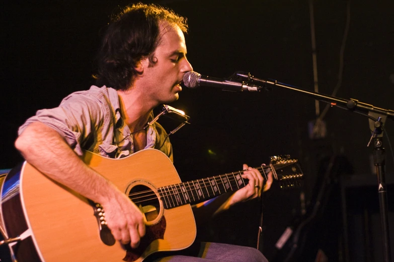 a man that is sitting down playing guitar