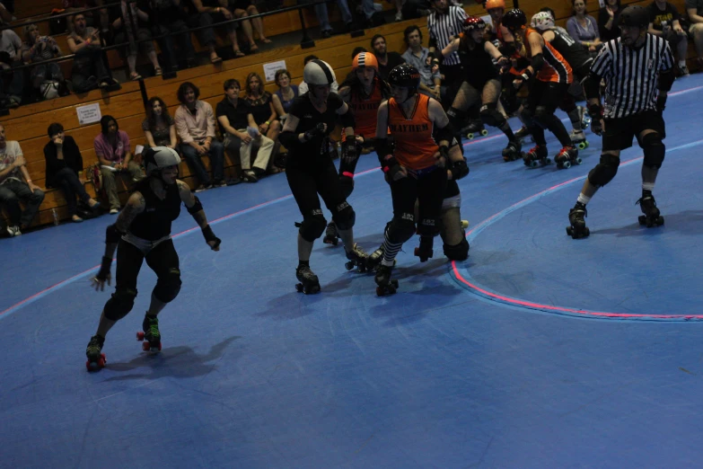 four people are skating in a rink with a referee