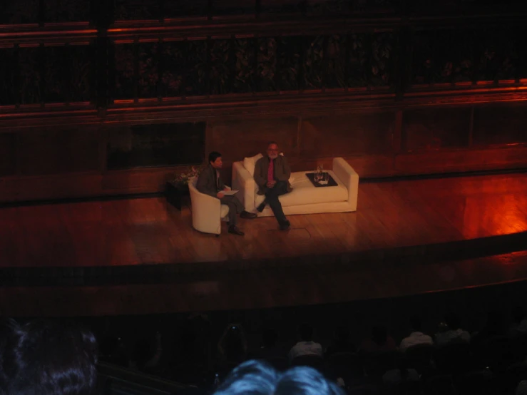 two men are sitting on couches facing each other