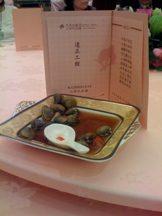 food items on a gold dish and chinese paper on a pink table