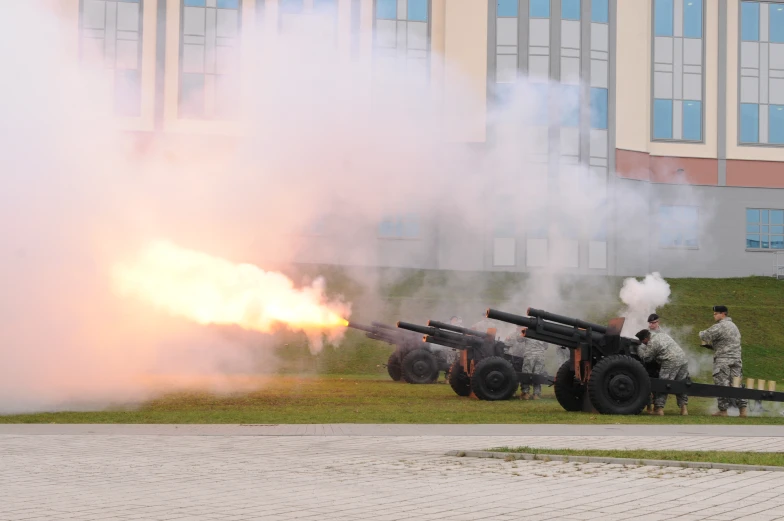 two men stand near some artillery guns that are spinning