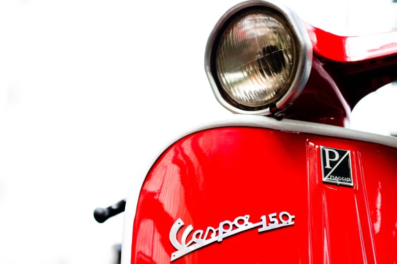 a closeup po of a front view of an older style moped with a headlamps and a lens on top