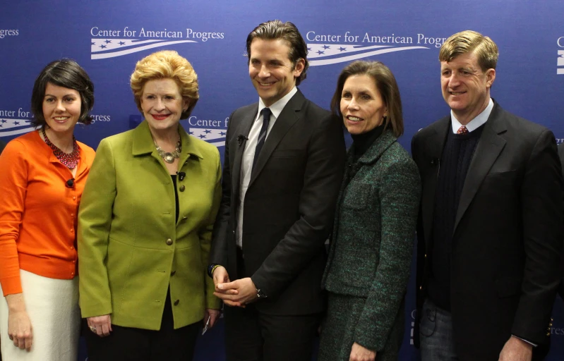 the group of four people standing in front of a wall smiling