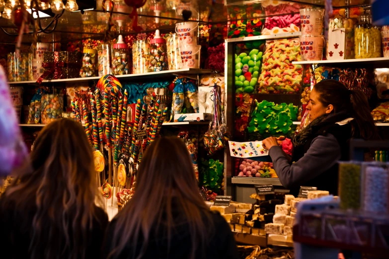 two women in front of shelves with candy and beads