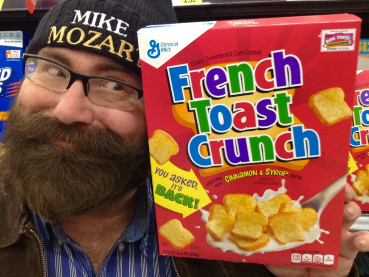 a man with a mustache reading a box of french toast crunch