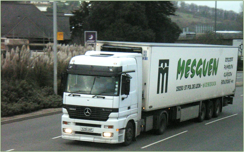 a white truck is on the street next to a field