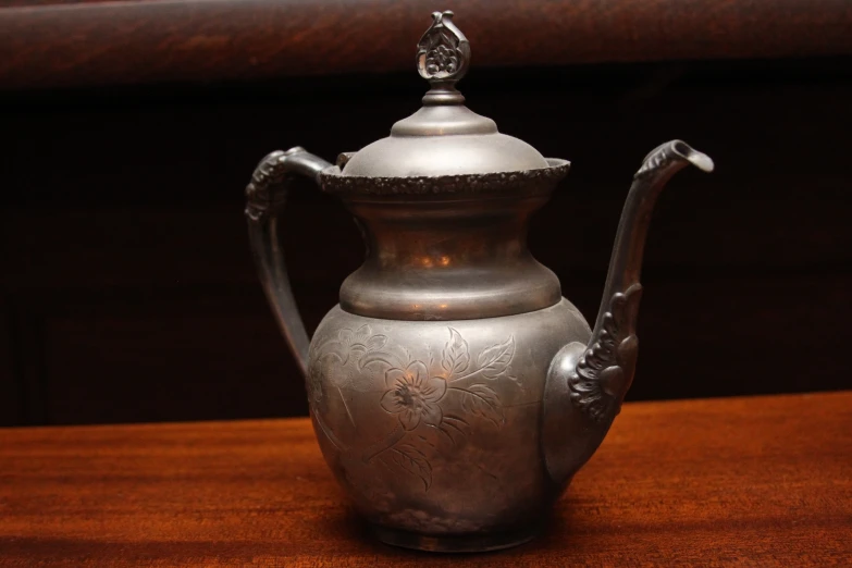 a silver metal teapot sitting on top of a table