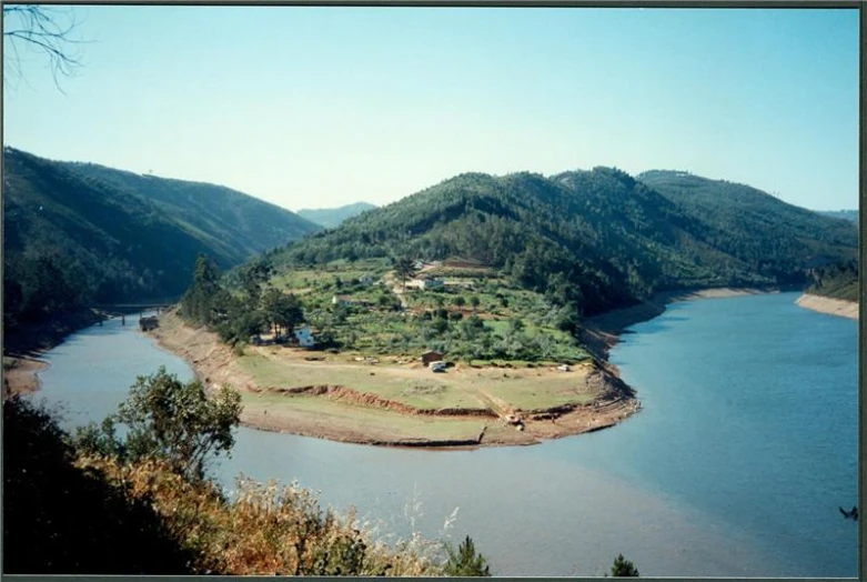 the view from a high viewpoint shows a mountain, river and a few houses