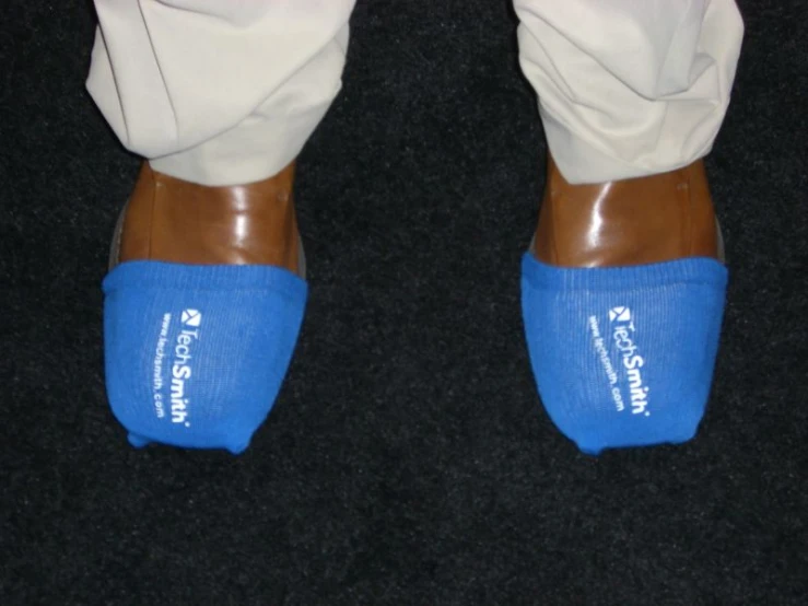 a person wearing blue slippers and white pants with black feet