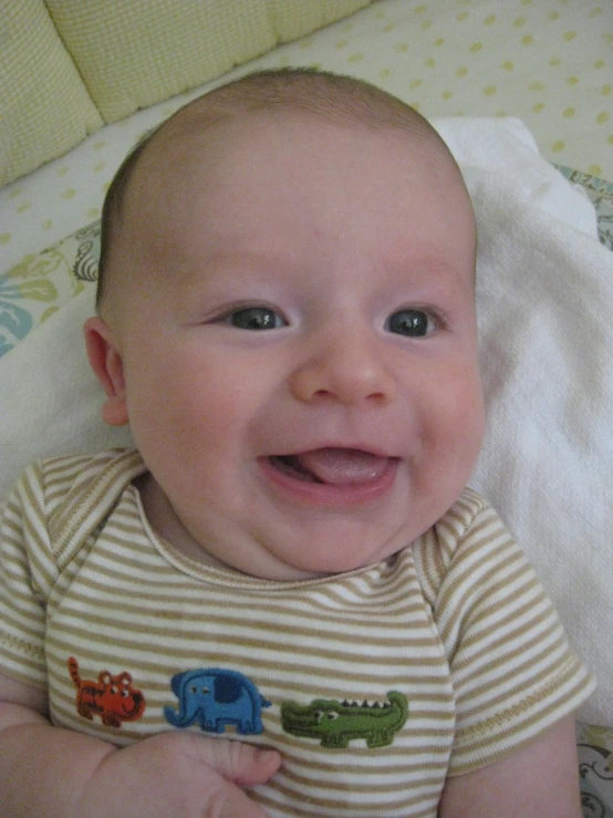 an infant in a striped shirt smiles at the camera