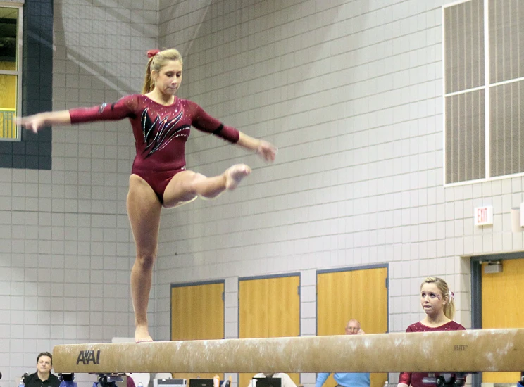 a woman on a beam on the gymnastics court