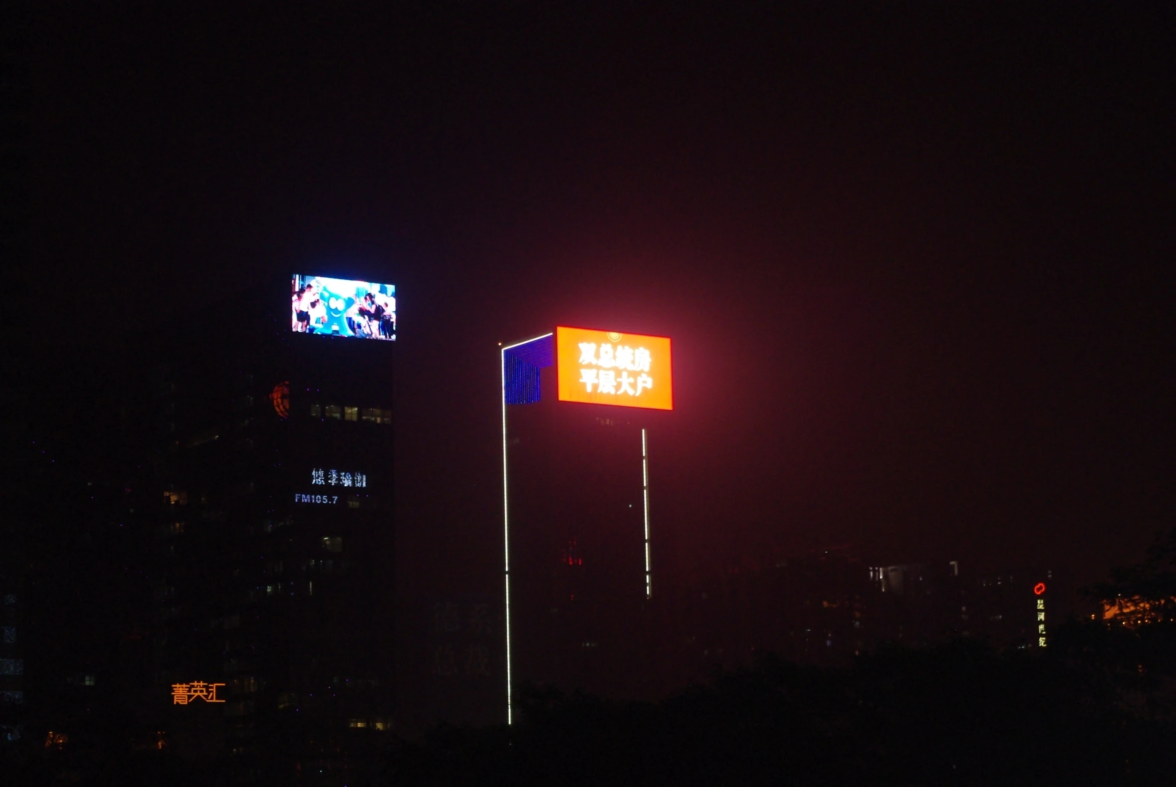 some very tall buildings at night and there is a screen