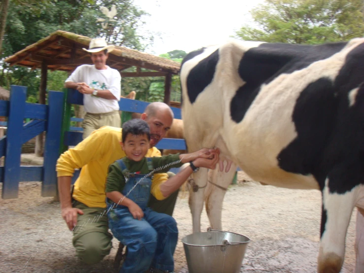 a man and boy petting a black and white cow