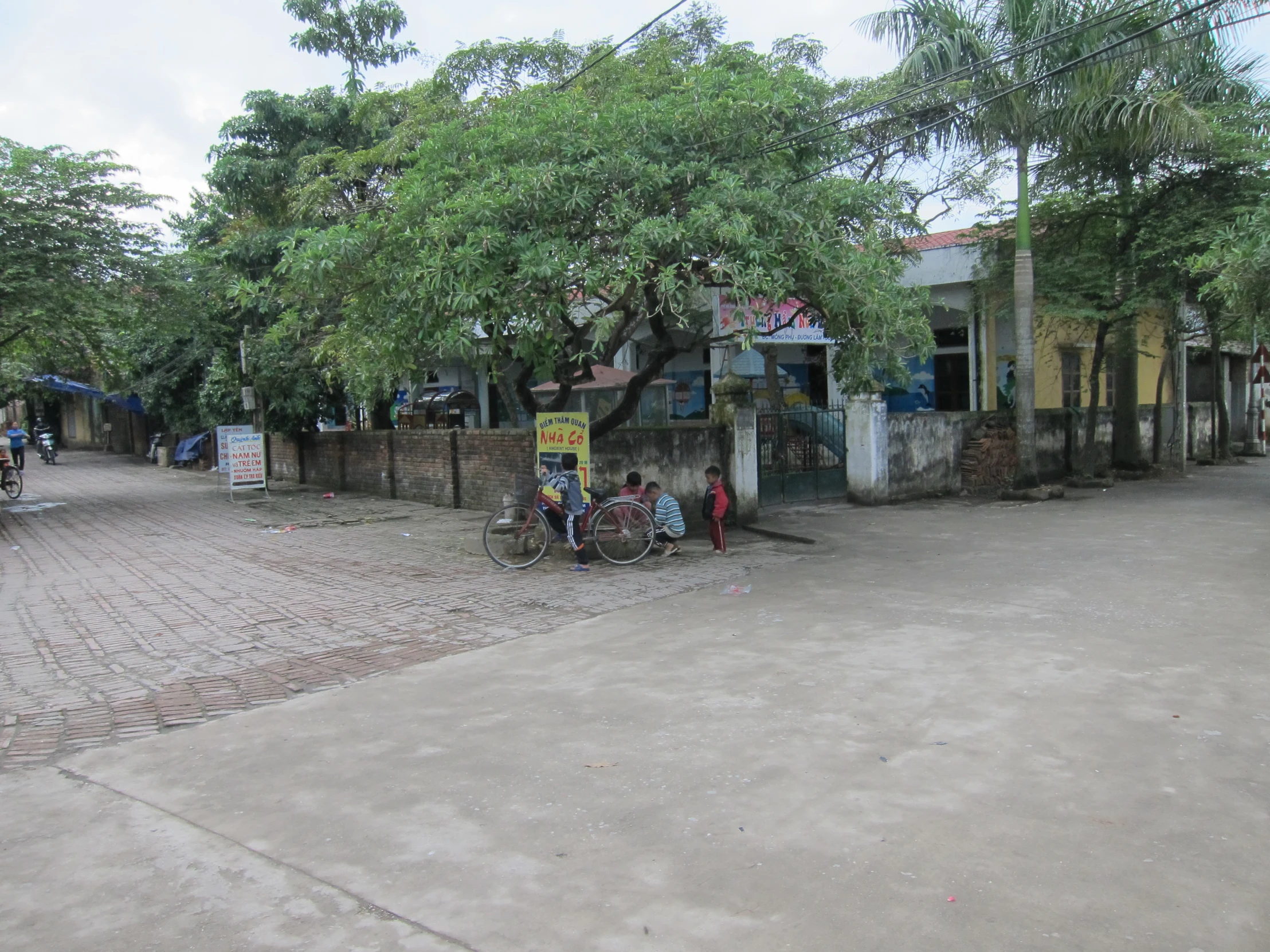 people walking around a street with buildings, trees and signs