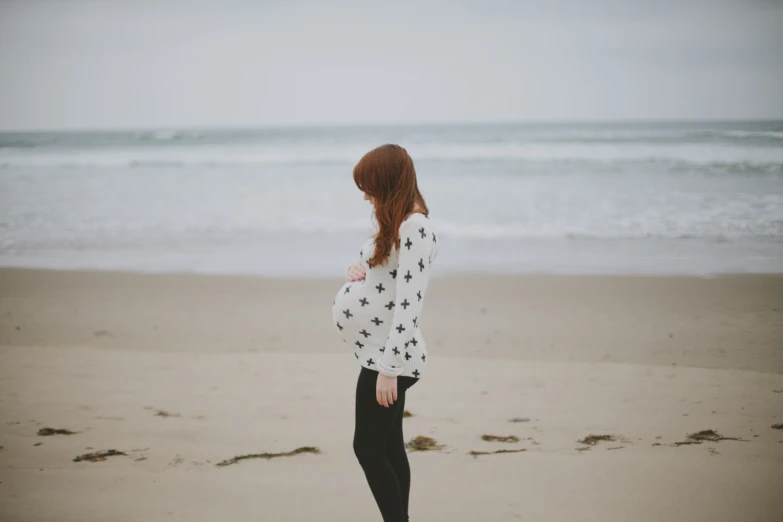 the young woman is standing at the beach looking out over the water