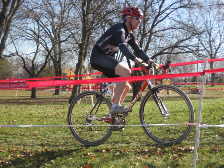 a man riding a bike around a red tape