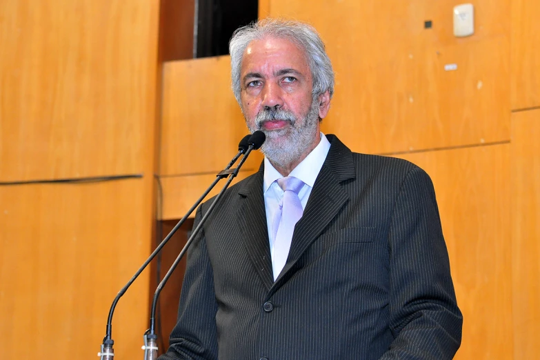 an older man with a white beard is standing at a podium