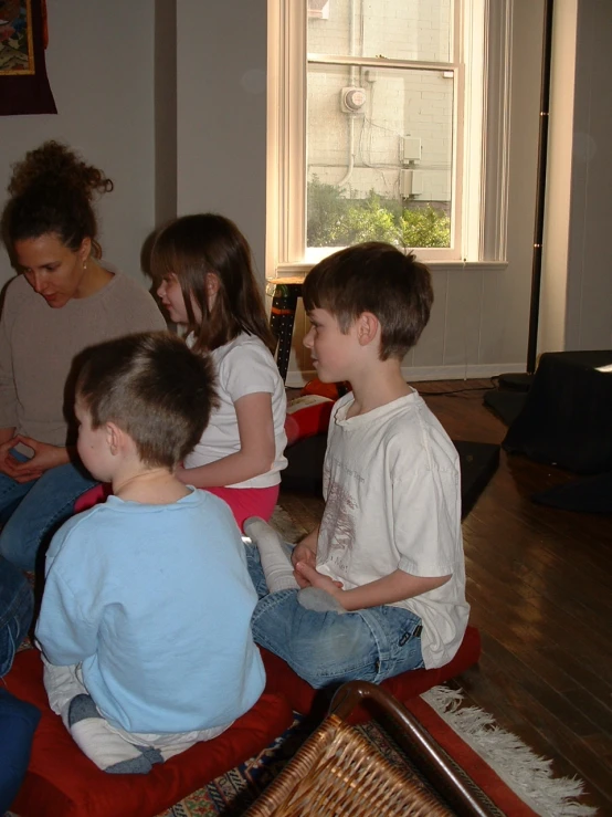 a woman sitting in front of two children and a woman looking at soing on the other side