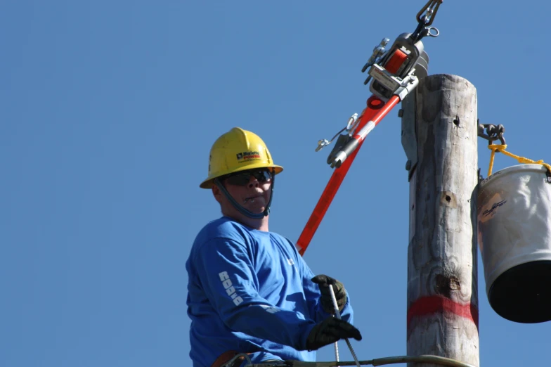 a man standing next to a telephone pole with a large power pole attached