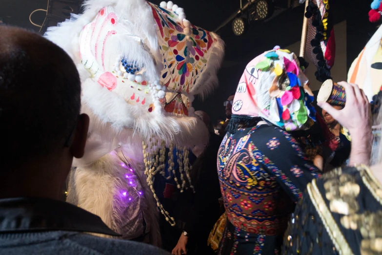 a woman with colorful head dress standing next to a man