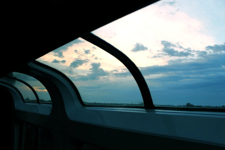 a passenger train with the sun shining through clouds