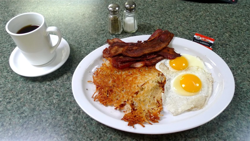 an english breakfast with bacon and eggs on a white plate