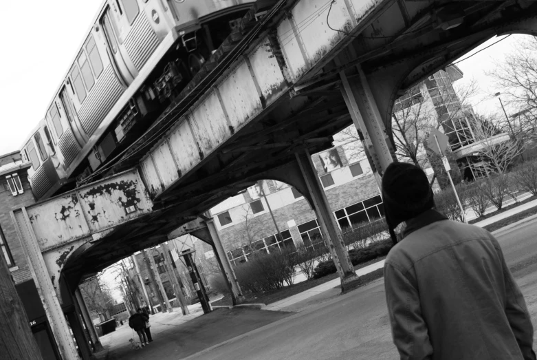 the person is walking under the train track over the water