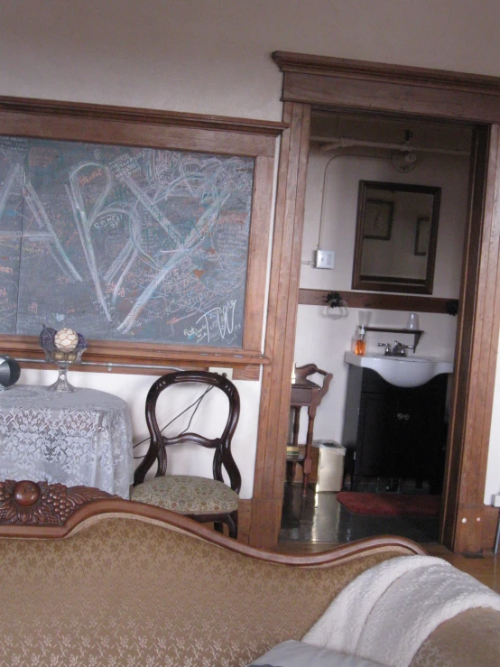 a living room with a sofa, a table and large chalk board