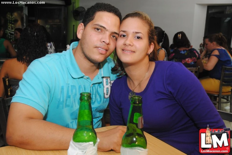 two people that are sitting together and one is holding onto bottles