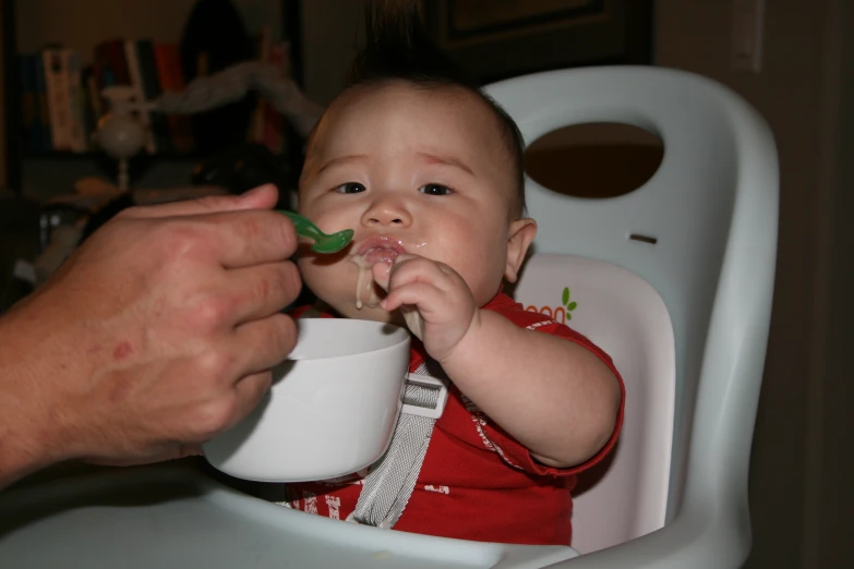 a man feeding a baby a spoon full of food