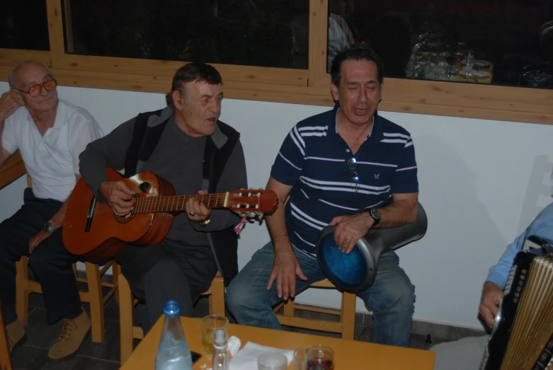 a group of men sitting around a table playing instruments