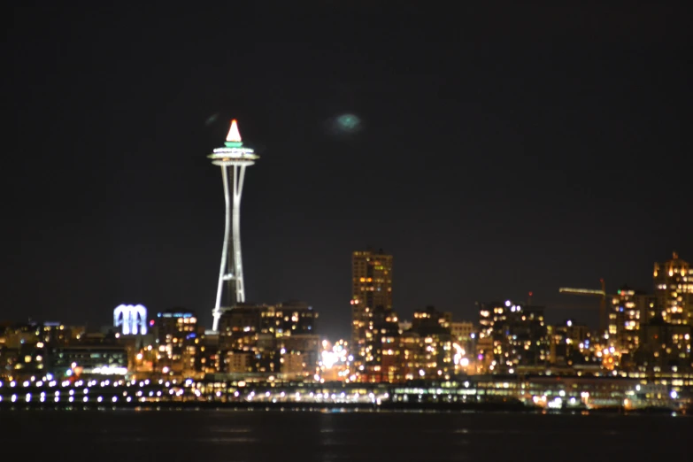 a city skyline with a tall, illuminated water tower in the distance