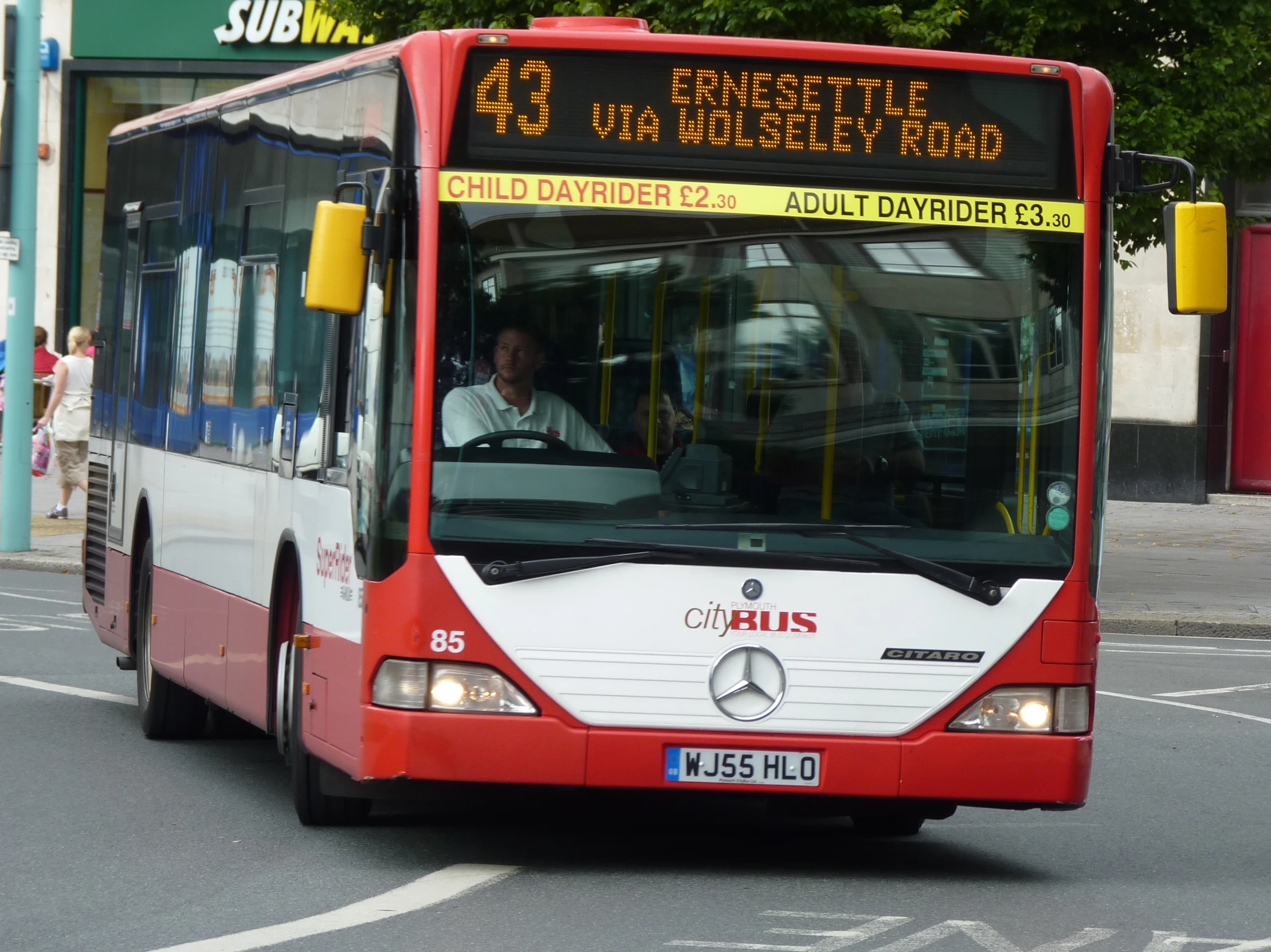 a red, white and black passenger bus driving down the street