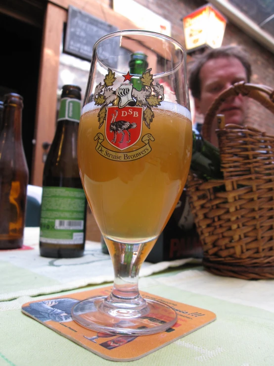 a glass of beer on a table with bottles in the background