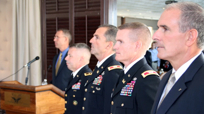 a group of uniformed soldiers standing next to each other in front of microphone