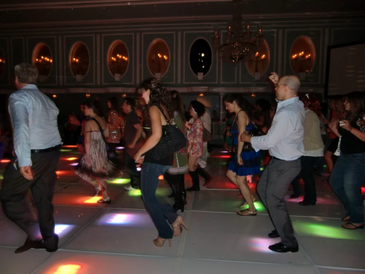 several people dancing with colored lights on the floor