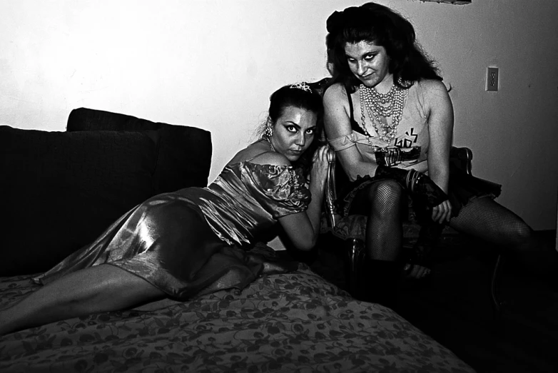 two women sitting on a bed near one another