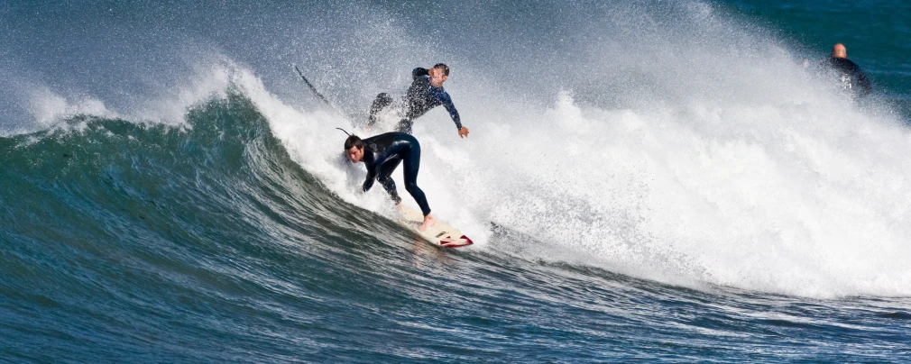 two people riding a wave on top of surf boards