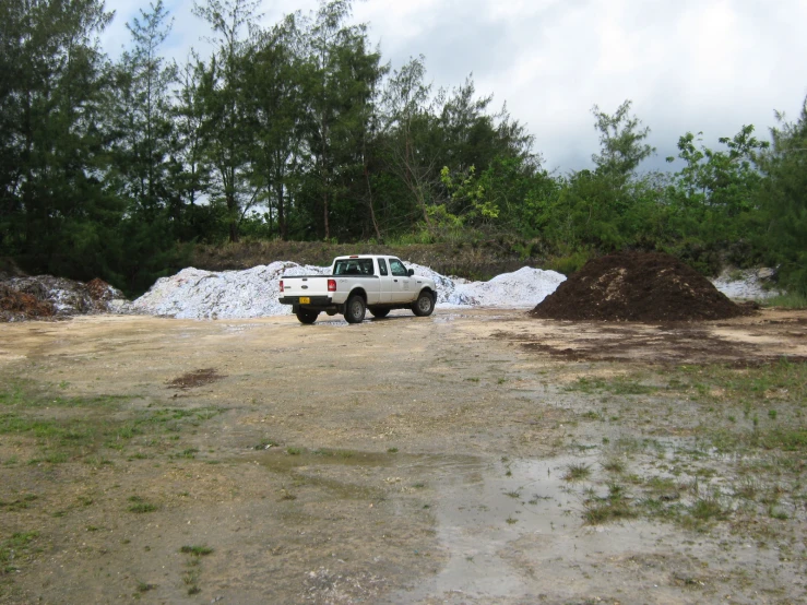 a large pile of dirt sits near the white pick up truck