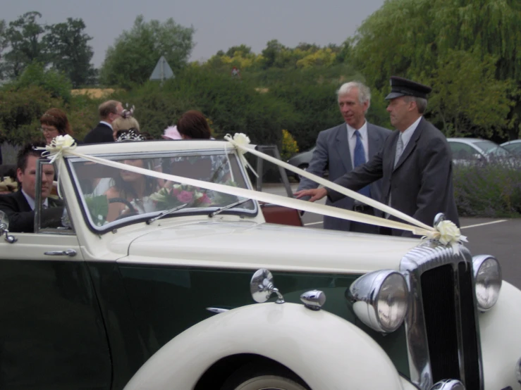 two men dressed in suits with ribbons on the top and side of a car