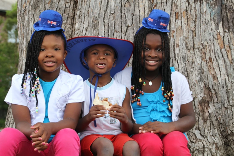 three s sit next to each other in front of a tree