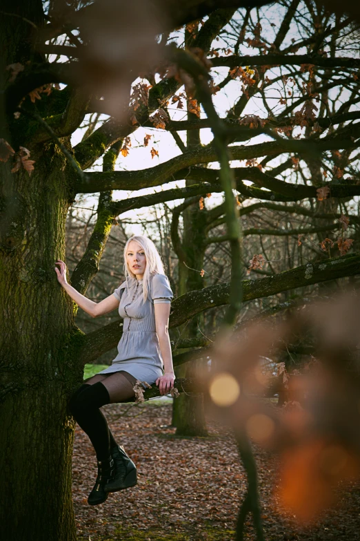 a woman sitting on a tree nch while posing for the camera