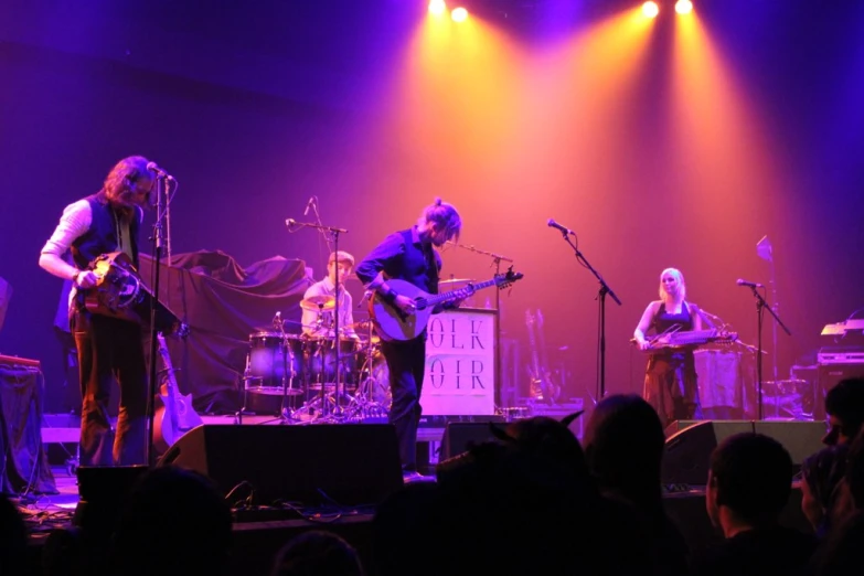 the band is performing on stage with purple lights