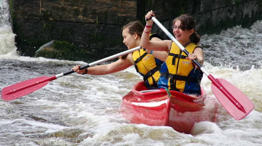 two people with paddles in a boat going through a river