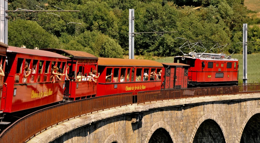 a large red train riding on the tracks near a bridge