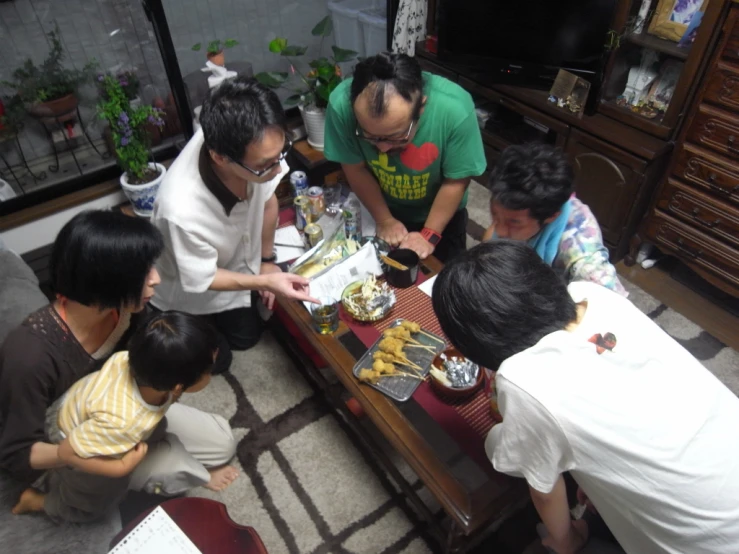 group of people gathered around a table eating food