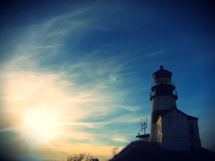 the sun is rising and the lighthouse is silhouetted