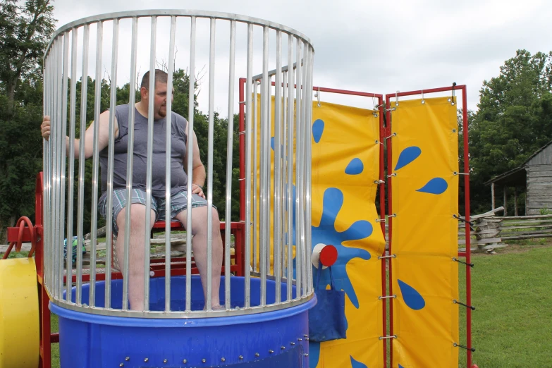 a man sits in a cage next to a toy